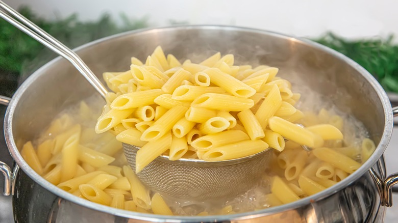 pasta being taken from a pot of water