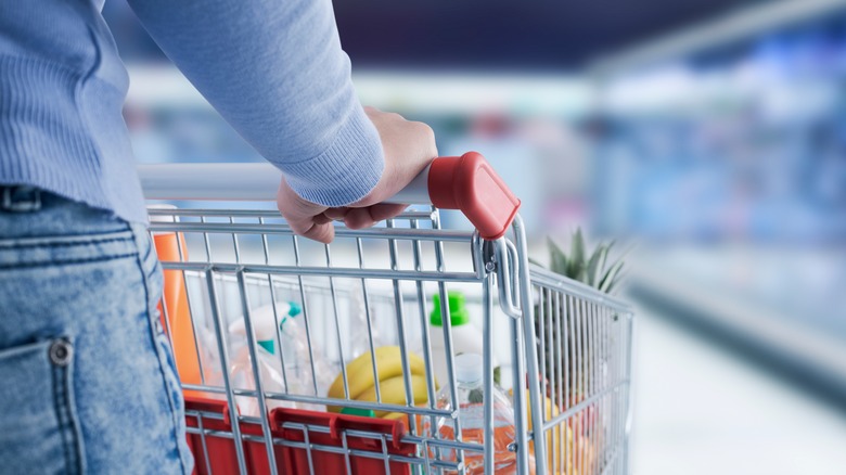 customer pushing shopping cart filled with food