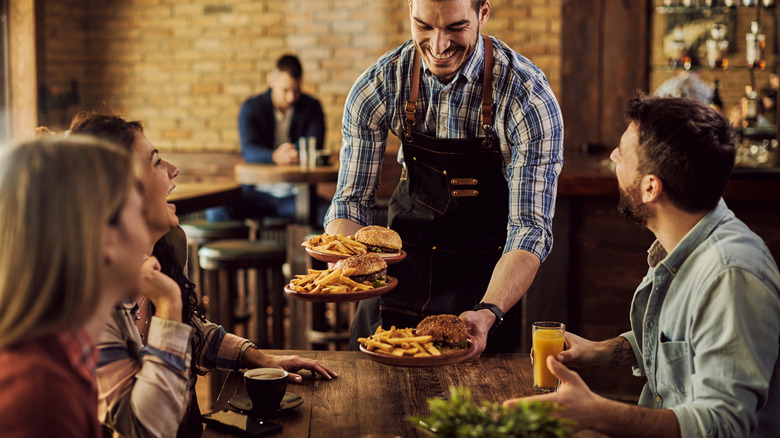 waiter serving people food at restaurant