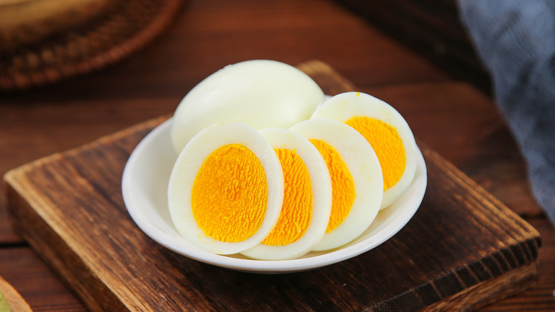Sliced, hard boiled eggs on a wooden board